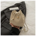 Dettaglio di una borsa a secchiello in paglia beige con chiusura a coulisse dorata - Bianco Sporco