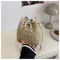 Gros plan du sac seau en paille fait main avec cordon blanc et détails de perles dorées - Kaki