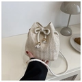 Gros plan du sac seau en paille tressée avec cordon de serrage et perles dorées - Blanc Cassé