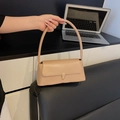 Minimalistische beige Schultertasche aus Leder mit goldener Schnalle im Alltagsszenario - Khaki