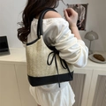 Beige Stroh-Tote-Bag mit schwarzem Lederbesatz und Schleife, am Modell getragen - Schwarz