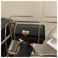 Detailed view of a black leather flap bag with gold chain strap held in hand - Black