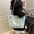 Groen en paars gestreepte canvas draagtas met modieus label gedragen door model - Groen