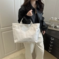 Metallic silver large tote bag with Tyvek texture worn by model in a modern home setting - White