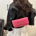 Hot pink envelope chain bag with a gold bow buckle worn by a model in a minimal setting - Pink