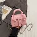 Rosa Mini-Quadrat-Tasche mit Silberschnalle und Kette vor grauem Anzug-Hintergrund - Rosa