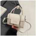 Detail der cremefarbenen Lederhandtasche mit goldenem Logo und feiner Narbung - Weiß