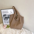 Borsa tote in maglia marrone all'uncinetto con tracolla larga appoggiata alla parete - Cachi
