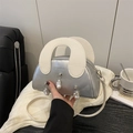 Silberne Shell-Tasche mit weißem Griff und Barockperlen auf schwarzem Ledersofa - Weiß