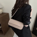 Beige faux leather underarm baguette bag with gold lettering shown on a model - Khaki