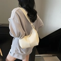 Chic cream leather hobo bag with adjustable strap worn by model for commuter style - Off White