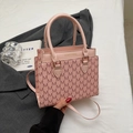 Vue détaillée du sac rose à monogramme avec texte doré sur un blazer gris - Rose