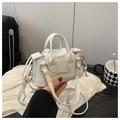Detail van witte mini-handtas met lychee-patroon, goudkleurig logo en schouderband - Wit