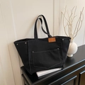 Minimalist black canvas tote bag with contrast stitching and brown leather label detail - Black