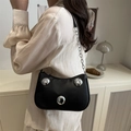 Bolso de mano negro chic con tachuelas plateadas y correa de cadena en una modelo - Negro