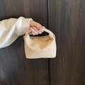 Beige woven small square handbag with golden hardware being held against wood background - Khaki