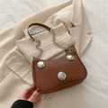 Bolso medialuna de cuero marrón con tachuelas plateadas y cadena sobre blazer blanco - Marrón