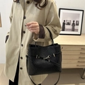 Minimalist black tote bag with woven texture, metal buckle and adjustable strap shown by model - Black