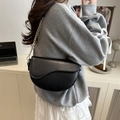 Sac selle noir classique avec bandoulière chaîne dorée porté par un mannequin chic - Noir