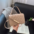 Beige gesteppte Umhängetasche mit goldener Schnalle und Kettenriemen in einer Lifestyle-Ansicht - Khaki