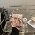 Pink leather box crossbody bag with silk scarf handle and plush ball charm accessory - Pink With White Long-Legged Pendant