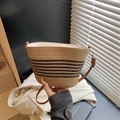 French style straw bucket bag with black stripes and brown leather strap held by hand - Khaki and Black