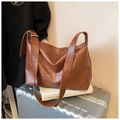 Detailaufnahme der Vintage-Leder-Einkaufstasche in Karamell mit breitem Gurt auf Koffer - Braun