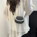 Elegant black shell-shaped crossbody bag with pearl strap worn by a female model - Black