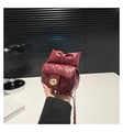 Close-up of wine red quilted chain bag with bow detail and gold twist lock clasp - Red