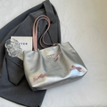Silver matte tote bag featuring pink ribbons and metal heart charms on grey blazer - Silver
