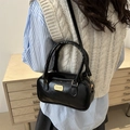 Glossy black bowling bag with gold hardware and adjustable crossbody strap on model - Black