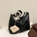 Close-up of black textured leather tote bag with a cute plush charm and wide strap - Black (With Charm)