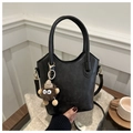 Detail of black leather tote bag with monster charm on a cozy coffee table background - With Pendant Style / Black