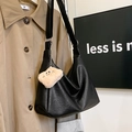 Detalle de bolso medialuna de cuero negro con colgante de peluche y correa de lona - Con Colgante / Negro