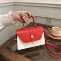 Borsa a tracolla bicolore rossa e bianca con fibbia dorata su tavolo in legno - Rosso
