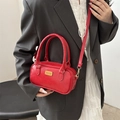 Red faux leather bowling handbag with gold logo for women, worn with grey blazer suit - Red