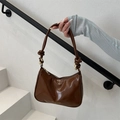 Glänzende Schultertasche aus Lackleder in Karamell mit Knotendetail und Goldbeschlägen - Braun