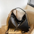 Minimalist black leather tote bag with silver hardware on a beige chair for casual commute - Black