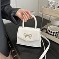 Chic white mini crossbody bag with a delicate gold bow accent and leather finish - White