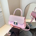 Pink sequin crossbody bag with gold buckle and top handle shown in a hand-held view - Pink