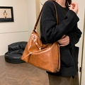 Brown faux leather tote bag with adjustable shoulder strap in minimalist indoor setting - Brown