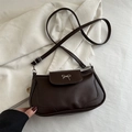 Dark brown leather saddle bag featuring a silver bow metal accent and adjustable strap - Brown