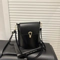 Minimalist black bucket bag with smooth leather finish and unique gold metal lock - Black
