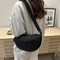 Minimalistische schwarze Nylon-Halbmondtasche am Modell in modernem Innendesign - Schwarz