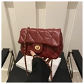 Detail of dark red quilted leather handbag with gold metal twist lock and chain strap - Red