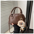 Detail of coffee brown leather bag with Lucky OHIO embossed text and soft plush charm - Brown with Pendant