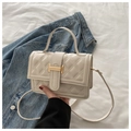 Primer plano del bolso bandolera acolchado beige con hebilla de metal dorado - Blanco