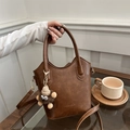 Vintage brown leather bucket bag with plush charm and long strap on a cafe table - Brown (With Charm)