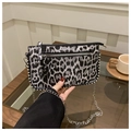 Detalle de bolso leopardo con tachuelas plateadas y cadena metálica en un café - Estampado de Leopardo Negro