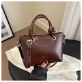 Détail d'un sac seau en cuir marron foncé brillant avec poignée nouée et finitions dorées - Marron